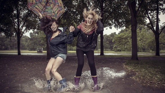 Das Bild zeigt zwei tanzende und springende Mädchen im Regen. © Imago / Westend61 Foto: Westend61