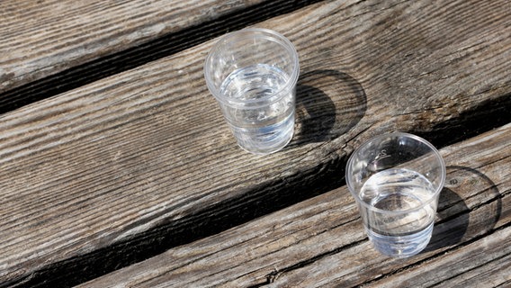 Zwei Schnaps-Gläser mit einer durchsichtigen Flüssigkeit auf Holzuntergrund. © Helgi / photocase.de Foto: Helgi / photocase.de