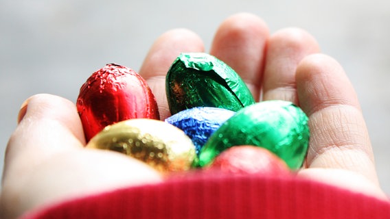 Sechs bunte Schokoladen Ostereier liegen in einer Hand. © photocase / Cattari Pons Foto: Cattari Pons