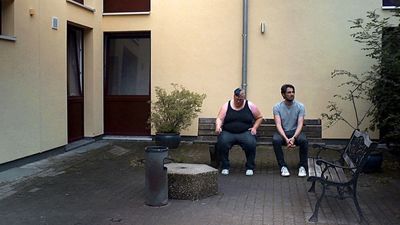 Zwei Menschen auf einer Bank in einem Innenhof. © NDR/Timo Grosspietsch Foto: Timo Grosspietsch