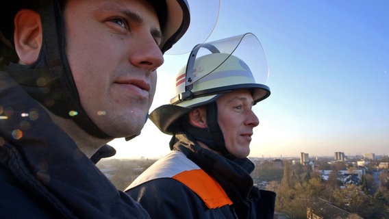 Hendrik Buth zusammen mit Feuerwehrmann Steven Eckardt auf der Drehleiter über Hamburg. © NDR/7 Tage Foto: Nikolas Müller