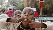Ein afrikanischer Junge streckt seine Zunge raus.  