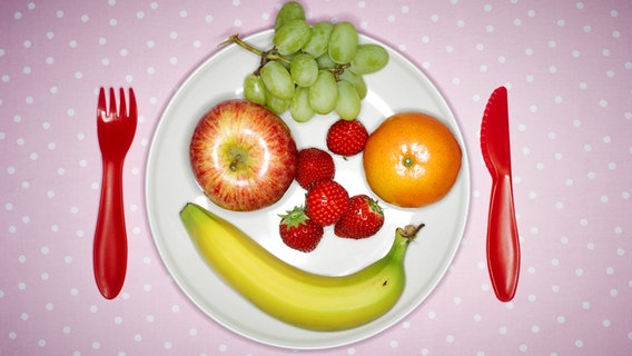 Auf einem Teller liegt Obst, das sich zu einem Smiley formt. © imago/Westend61 