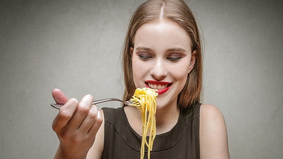 Junge Frau führt eine Gabel mit Spaghetti zum Mund. © Fotolia.com Foto: olly