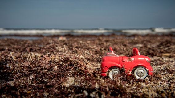 Ein rotes Spielzeugauto, steht einsam im Dreck auf dem Boden. © photocase.de / Catalenka Foto: photocase.de / Catalenka