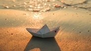 Ein Papierboot am Strand. © Unschuldslamm / photocase.de Foto: Unschuldslamm / photocase.de