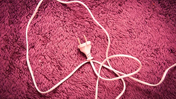 Ein Stecker inklusive Kabel liegt auf einem pinken Teppich. © suze / photocase.de Foto: suze / photocase.de