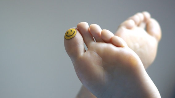 Zwei Füße mit einem Smiley auf dem großen Zeh des linken Fußes. © Seleneos / photocase.de Foto: Seleneos