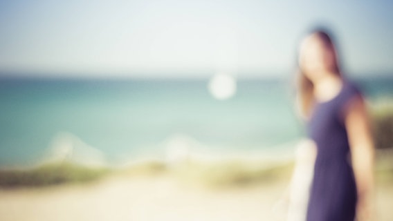 Ein unscharfes Bild, auf dem die Umrisse einer Frau an einem Strand zu sehen sind. © imago/Westend61 Foto: Westend61