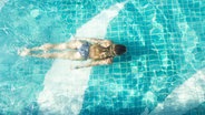 Eine Frau taucht in einem Pool. © imago/Westend61 Foto: Westend61