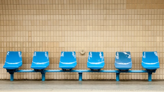 Eine Reihe von fünf blauen leeren Sitzen an einem Bahnhof. © HerrSpecht / photocase.de Foto: HerrSpecht / photocase.de