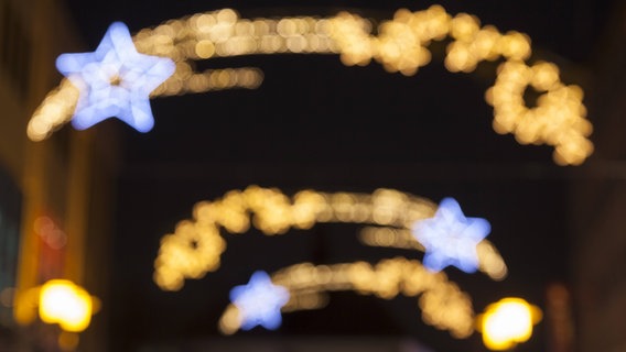 Das verschwommene leuchtende Eingangsschild eines Weihnachtsmarktes. © imago/Westend61 Foto: Westend61