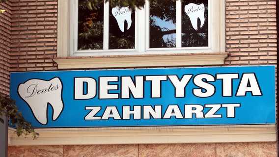 Das Schild eines deutsch-polnischen Zahnarzt hängt an der Fassade der Praxis.  Foto: Ralph Peters