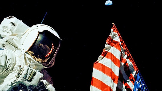 Harrison H. Schmitt steht neben der amerikanischen Flagge auf dem Mond. © NASA 