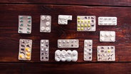 Das Bild zeigt mehrere halbvolle Pillenpackungen auf einem Holztisch. © Lucas1989 / photocase.de Foto: Lucas1989