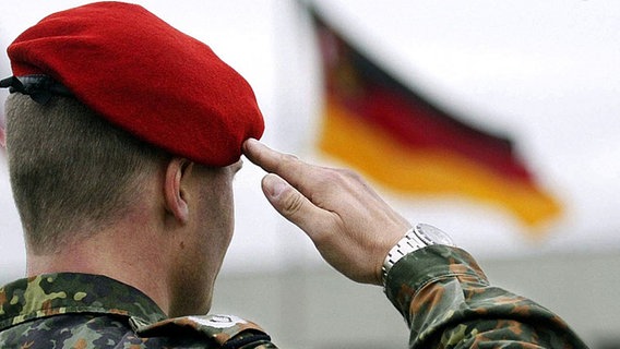 Soldat salutiert vor deutscher Fahne © picture-alliance / dpa 