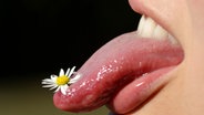 Frau steckt Zunge raus, auf deren Spitze ein Gänseblümchen. © picture-alliance.com 