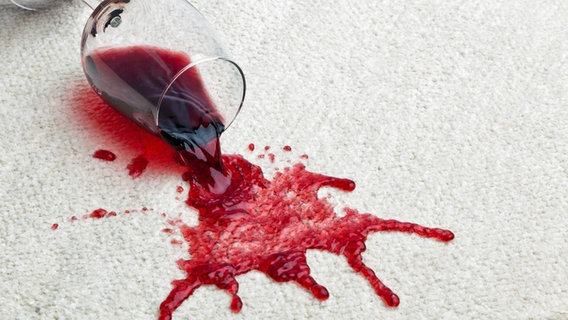Ein umgekipptes Rotwein-Glas besudelt den weißen Teppich ©  picture alliance/Bildagentur-online 