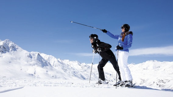 Zwei Skifahrer stehen auf einem Berg.  
