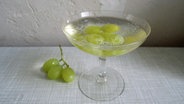 Ein Cocktailglas, in dem gekühlte Weintrauben als Eiswürfel fungieren. © NDR 