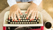 Zwei Hände mit roten Fingernägeln tippen auf einer alten Schreibmaschine. © Fotolia/peshkov 