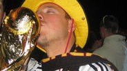 N-JOY Moderator Christian Haacke mit goldenem Pokal und Deutschlandtrikot im WM- Fußballfieber.  